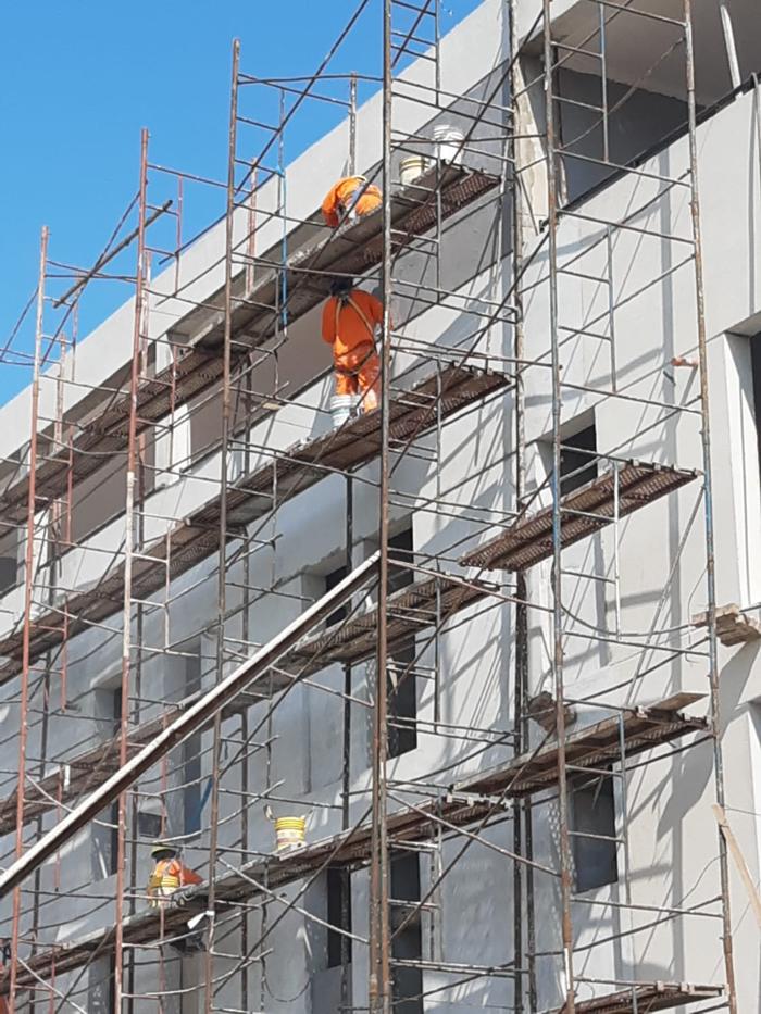 Frente de edificio con andamios y operarios